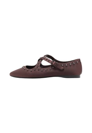 Zapato plano marrón puntiagudo con adornos de tachuelas y hebilla en la correa tipo Mary Jane, mostrado de perfil sobre fondo blanco.