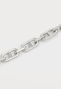 Silberne Metallkette mit länglichen ovalen Gliedern, die eine glatte Textur und ein poliertes Finish aufweisen, und ein modernes, minimalistisches Design präsentieren.