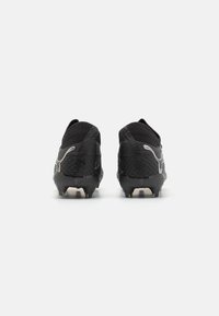 Svarta fotbollsskor med en texturerad överdel, elegant design och silverdetaljer. Utvecklade med inbyggda nubb för grepp och en strömlinjeformad bakprofil.