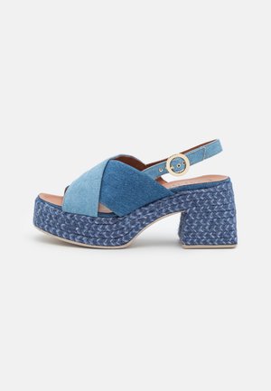 Sandale à plateforme en denim bleu avec brides croisées, bride de cheville ajustable avec boucle dorée et talon épais texturé.