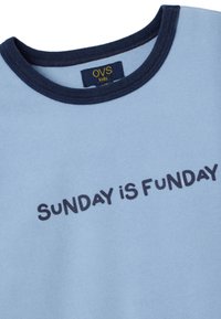 Camiseta de algodón azul claro con cuello redondo azul marino, que presenta el texto "SUNDAY IS FUNDAY" en un tipo de letra azul oscuro. Textura suave, diseño casual.
