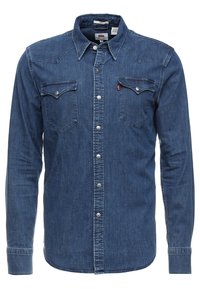 Tummansinisestä farkkupaidasta, jossa on pitkät hihat, terävä kaulus, kaksi rintataskua, hopeiset napit ja lännen tyyliin suunniteltu kaarroke.