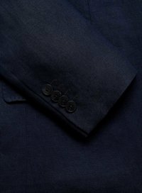 Blazer en lin bleu marine avec des manches ornées de quatre boutons noirs, affichant une texture lisse et une finition soignée, mettant en valeur des détails de confection sur mesure.