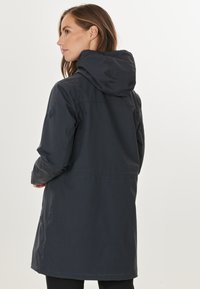 Donkergrijze gewatteerde parka met een middellange snit, zachte textuur en zijzakken. Beschikt over een logo op de linker mouw.