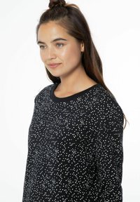 Maglione nero con motivo a pois bianchi, scollatura rotonda e rifiniture a coste. Tessuto morbido con vestibilità rilassata, adatto per un abbigliamento casual.