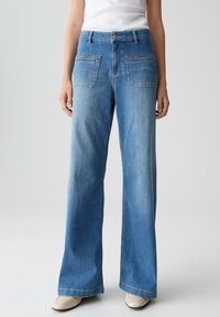 Weite blaue Jeans mit einem hellen Waschung, fünf Taschen, Gürtelschlaufen und einer klassischen Knopfverschluss. Glattes Denim-Material.