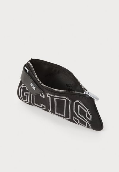 Pungă din material textil negru cu logo-ul brodat "GCDS", închidere cu fermoar și textură netedă. Prezintă o formă triunghiulară elegantă și accesorii din metal argintiu.