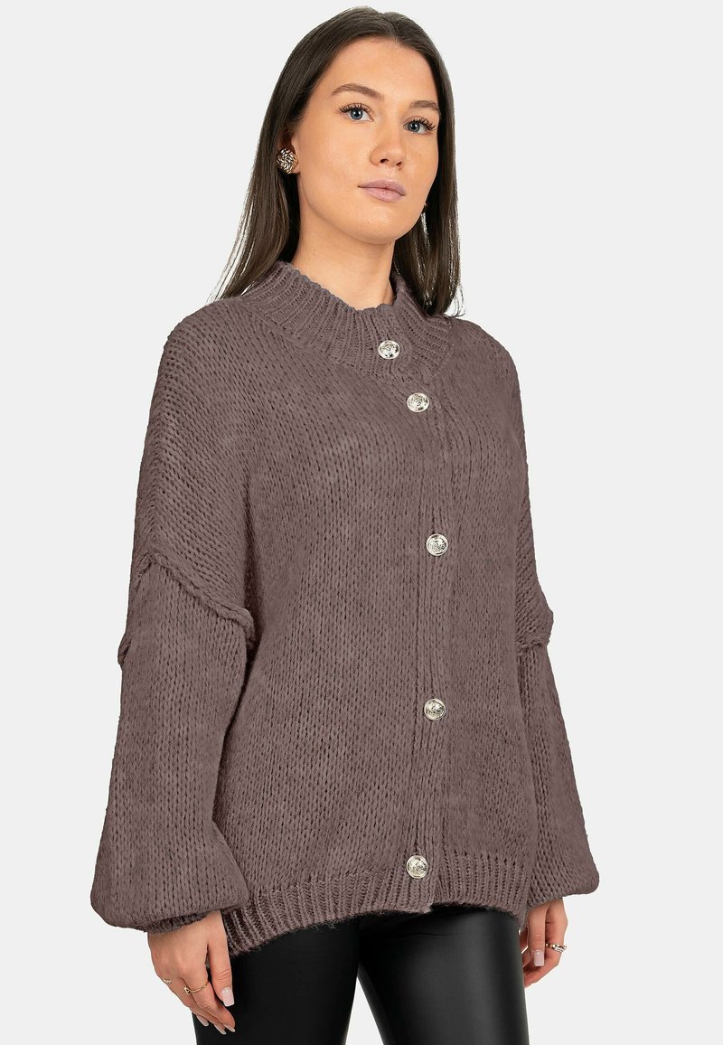 Pull en maille épaisse mauve avec col montant, manches oversize et boutons métalliques. Tissu texturé avec accents côtelés.