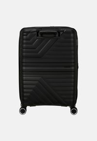 Valigia rigida nera con un design geometrico e testurizzato, dotata di manico superiore, ruote doppie e chiusura a zip.