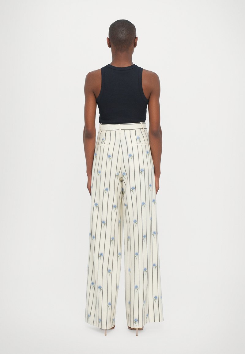 Wide-leg trousers in cream with blue floral patterns and vertical stripes. High-waisted design with a smooth texture and subtle pocket details.