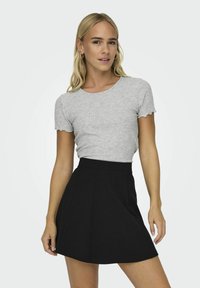 T-shirt grigia a costine con maniche a scallop abbinata a una gonna nera a tubino svasata. Design semplice, tessuto leggero e colori solidi.