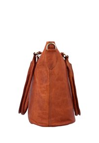 Brown leather handbag standing upright, showing its side with visible stitching and metal rings on top and sides.