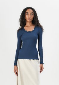Top de manga longa azul-marinho com decote rendado e acabamentos em renda nas mangas, design ajustado e textura suave.