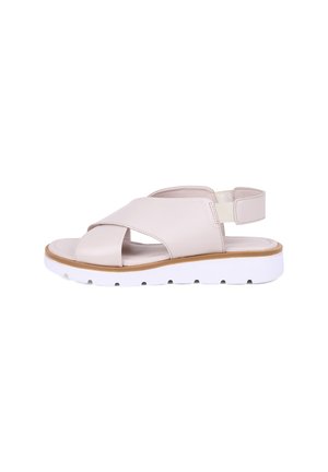 Beige Ledersandale mit breiten überkreuzten Riemen, elastischem Knöchelriemen, gepolstertem Fußbett und dicker weißer profillierter Sohle für Komfort und Halt.