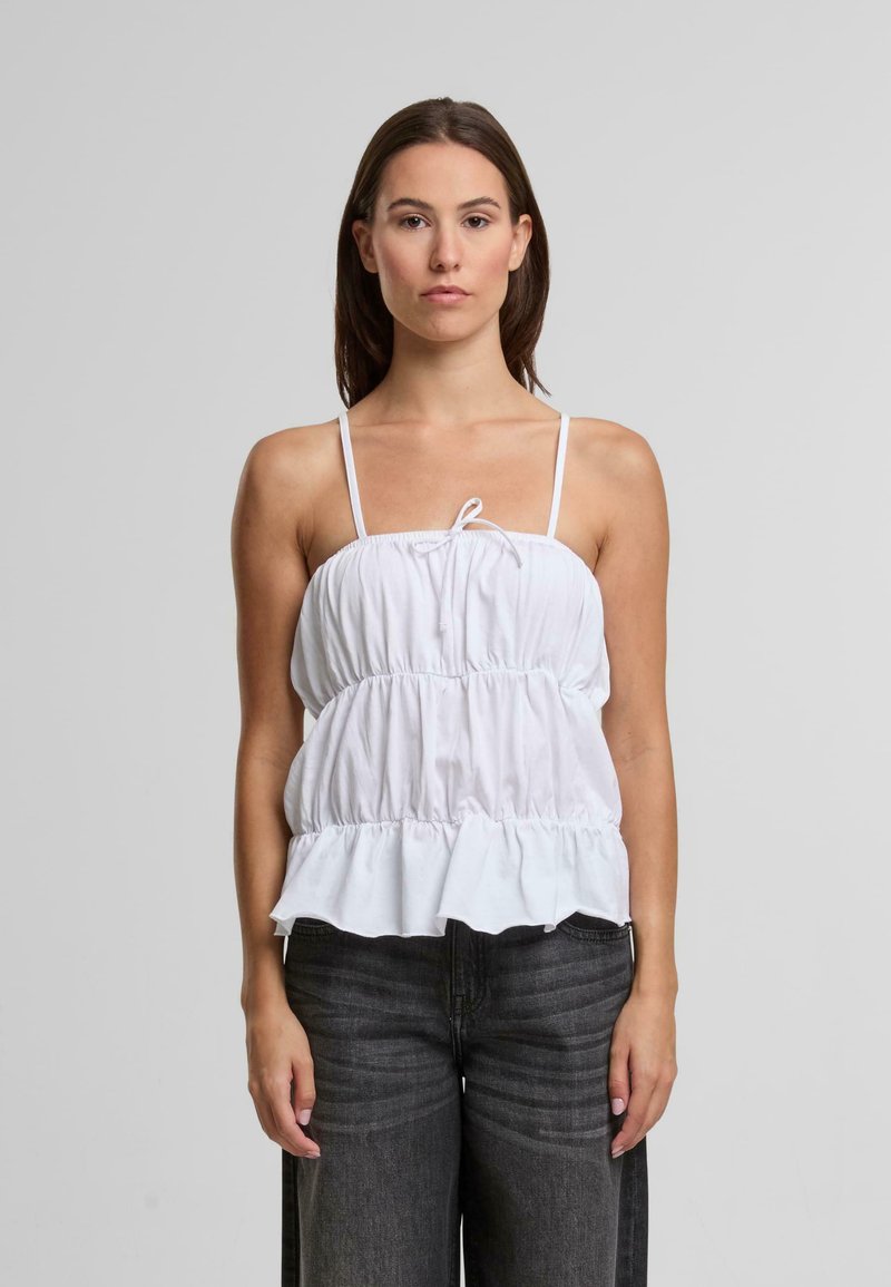 Biely bezramenný top s naťahovaným živôtikom a volánovým spodným okrajom. Vyrobený z ľahkej tkaniny, so šnúrkou vpredu a tenkými ramienkami.