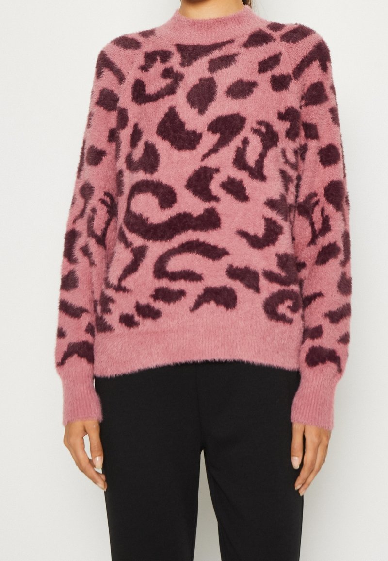 Rosa tröja gjord av mjukt, fluffigt material med ett mörkt burgundyrandigt leopardsmönster. Ribbad manschetter och nederkant, rund halsringning.