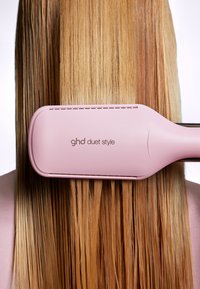 GHD Duet Style prostownica do włosów w kolorze różowym, o eleganckim designie i prostokątnej głowicy, sunąca po prostych, gładkich, blond włosach.