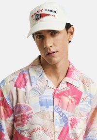 Korte mouw, knoopsluiting shirt met een kleurrijke, collage-stijl print van palmbomen, strandscènes en reisgerelateerde graphics.