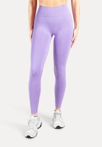 Leggings de cintura alta en color lila claro, hechos de un material elástico, con una textura suave y un diseño sin costuras que realza la forma de las piernas.