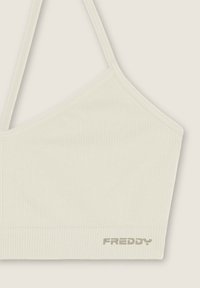 Bralette crema a costine con spalline sottili, caratterizzato da un design senza cuciture e un piccolo logo ricamato "FREDDY" in basso a sinistra.