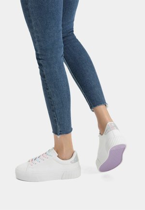 Vita sneakers med texturerad sula, pastellfärgade snören och iriserande klackdetalj. Bärs tillsammans med cropped blå denim, som visar upp trasig fåll.