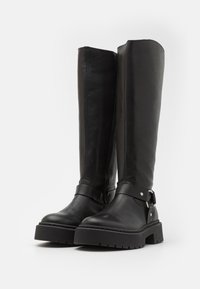 Botas negras de cuero hasta la rodilla con una textura suave, suelas gruesas y detalles de hebillas en el costado.