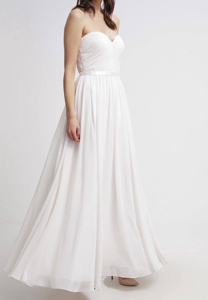 Robe blanche bustier avec un corsage ajusté et une texture plissée, une jupe fluide et une ceinture en satin. Tissu doux et léger qui tombe élégamment.