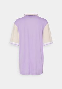 Lila Poloshirt mit beigen kurzen Ärmeln, ausgestattet mit weißen und lila gestreiften Akzenten an den Bündchen. Glatte Textur, lässige Passform.