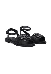 Schwarze Sandalen mit einer strukturierten Oberseite, Schnallen und einem Kreuzriemen-Design. Flache Sohle mit niedrigem Absatz für Komfort und Stabilität.
