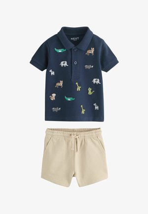 Tengerészkék kisgyermek póló színes állatmintákkal, bézs, gumis derekú, zsinóros rövidnadrággal párosítva.