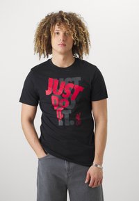 Svart t-skjorte med stor rød og grå tekst som sier "JUST DO IT" med "LFC"-logo i rødt, rund hals, laget av bomull, kortermet.