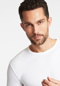 Weißes Langarmhemd, gerippte Struktur, runder Ausschnitt, enganliegendes Design. Verfügt über eine glatte Oberfläche und dezente Nähte am Ausschnitt.