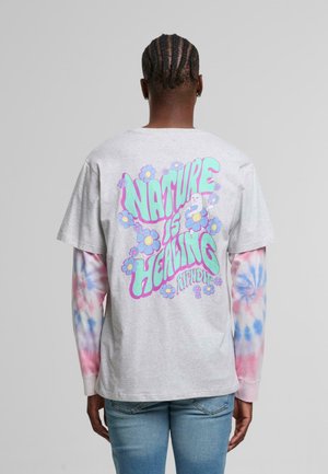 Graues T-Shirt mit buntem Grafikdesign auf der Rückseite, das "NATURE IS HEALING" und Blumendesigns zeigt, kombiniert mit langärmligen Tie-Dye-Ärmeln.