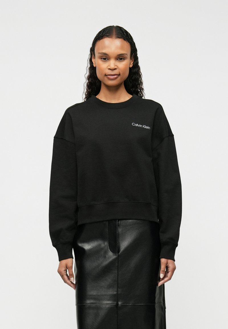 Μαύρο φούτερ από βαμβακερό μείγμα με στρογγυλή λαιμόκοψη και πτώσεις στους ώμους, με λευκό λογότυπο "Calvin Klein" στο αριστερό στήθος.