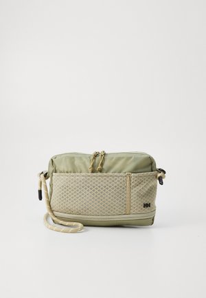 Bolso bandolera compacto verde claro con bolsillo frontal de malla, cierre de cremallera y correa ajustable de cuerda, colocado sobre un fondo blanco.