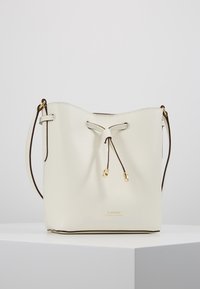 Krémová kožená kabelka ve tvaru kbelíku s nastavitelným popruhem, stahovací šňůrkou s zlatými konci a malým zlatým logem "Lauren Ralph Lauren" na přední straně.