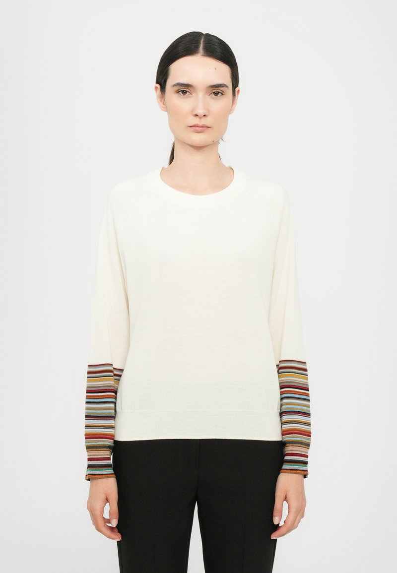 Maglione crema con accenti a strisce multicolori sulle maniche, caratterizzato da un colletto rotondo, orli a coste e un design dal fit rilassato.