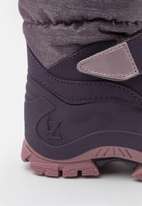 Botte d'hiver violette avec un revêtement texturé, un panneau violet lisse, des accents roses et une semelle en caoutchouc robuste avec des motifs de crampons bien marqués.