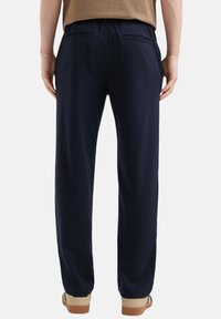 Marineblauwe joggingsbroek met een elastische tailleband, twee achterzakken en een relaxte pasvorm. Gemaakt van zachte stof met een gladde textuur.
