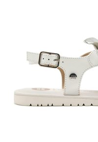 Sandalía de cuero blanca con tira en el tobillo y hebilla plateada, planta texturizada y suela de goma blanca con bordes en serrucho.