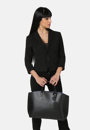 Borsa tote in pelle nera con manici doppi, texture liscia e forma rettangolare. Presenta un'etichetta con dettagli del marchio.