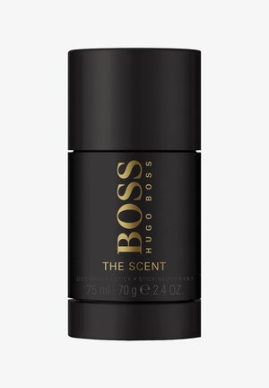 Dezodorant w sztyfcie Hugo Boss The Scent, czarny pojemnik ze złotym napisem, cylindryczny kształt, oznaczony szczegółami produktu i wagą.