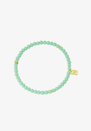 Bracelet extensible avec petites perles rondes vert clair et trois anneaux intercalaires en or, avec une petite étiquette en or ornée d'un symbole de cœur.