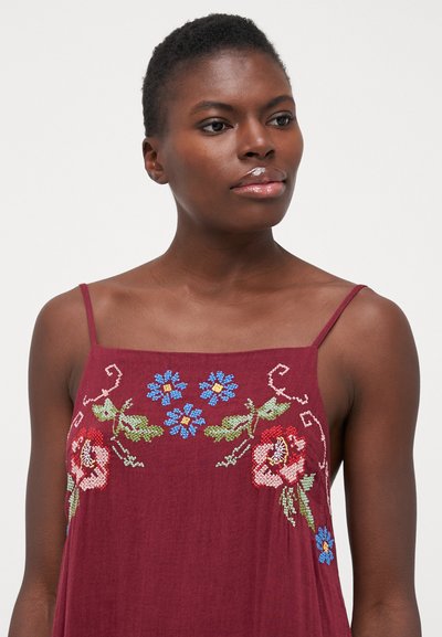 Abito bordeaux con spalline sottili, caratterizzato da ricami floreali colorati in verde, rosa, blu e bianco. Tessuto leggero con una consistenza morbida.