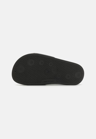 Schwarze Gummisohle mit strukturiertem Oberflächen, kreisförmigen und ovalen Grip-Mustern sowie dem Aufdruck "MADE IN ITALY" in der Nähe der Mitte.