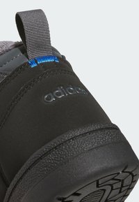 Μαύρη φτέρνα αθλητικού παπουτσιού Adidas με υφασμένη σόλα και γκρι ταινία έλξης με μπλε ραφή.