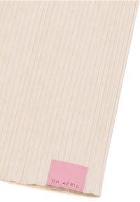 Tissu beige côtelé avec une étiquette rectangulaire rose cousue sur le bord inférieur indiquant « OH APRIL » en texte noir.