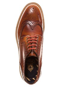 Chaussure brogue en cuir brun poli pour homme avec des lacets rouges, design en pointe et perforations détaillées, vue de dessus sur fond blanc.