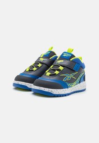 Scarpe sportive in blu e grigio con accenti verde neon. Presentano cinturini in velcro e suole testurizzate. Dettaglio grafico distintivo di un dinosauro.