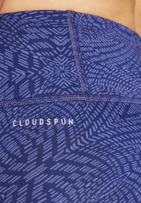 Leggings blu navy con un motivo geometrico. Realizzati in un tessuto morbido, presentano cuciture piatte e il logo "CLOUDSPUN" in bianco vicino alla vita.
